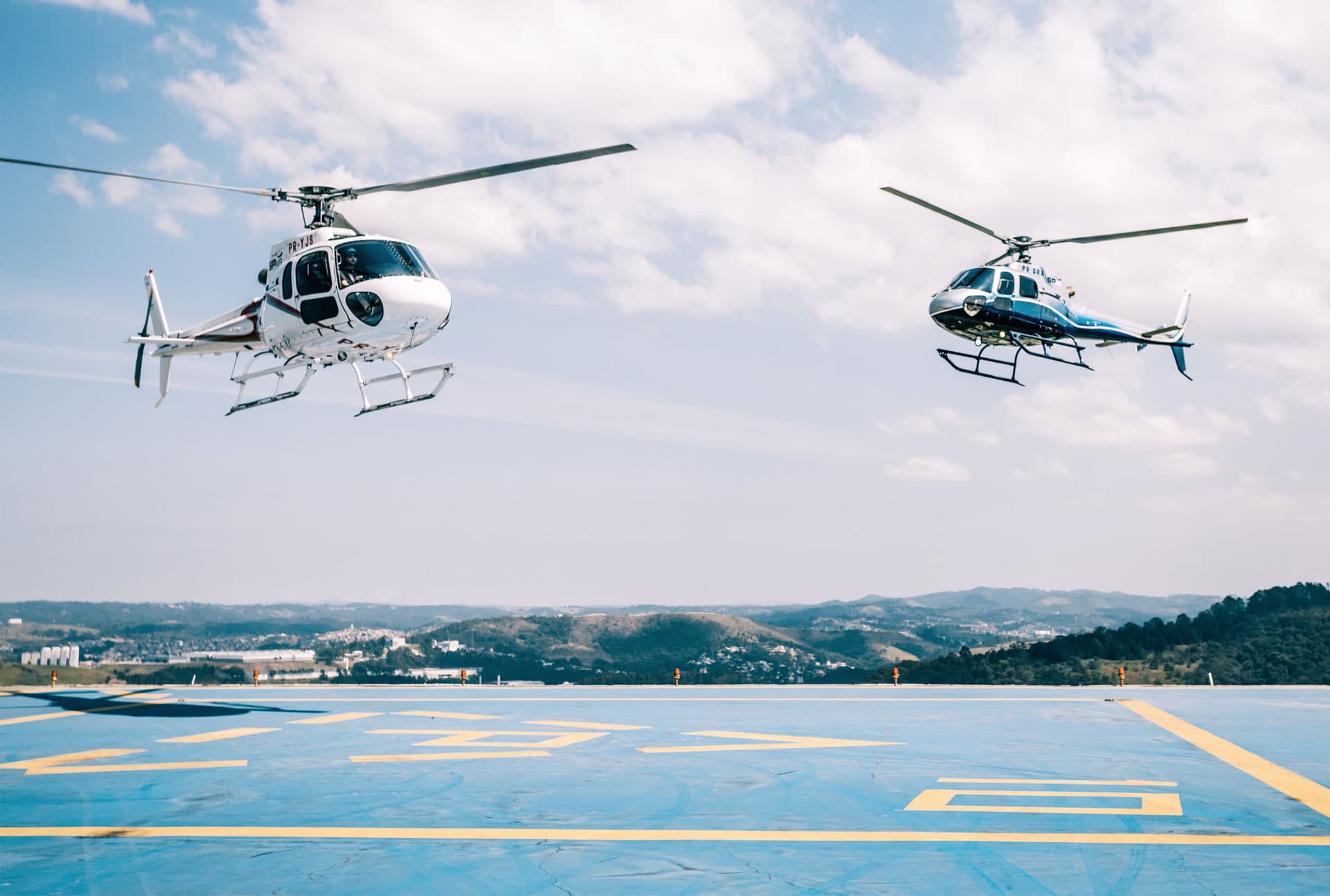 Dois helicópteros AS350 da SPAir decolando do heliporto da base em Barueri